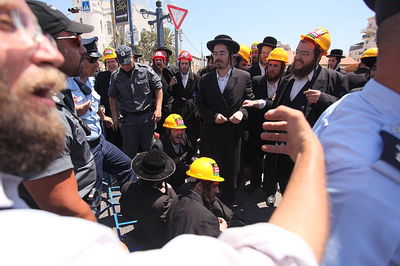 צפו: שוטר מושך באכזריות בפיאותיו של מפגין חרדי