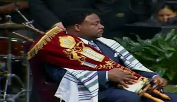 מטיף התעטף בטלית וביריעות ספר-תורה במהלך טקס נוצרי