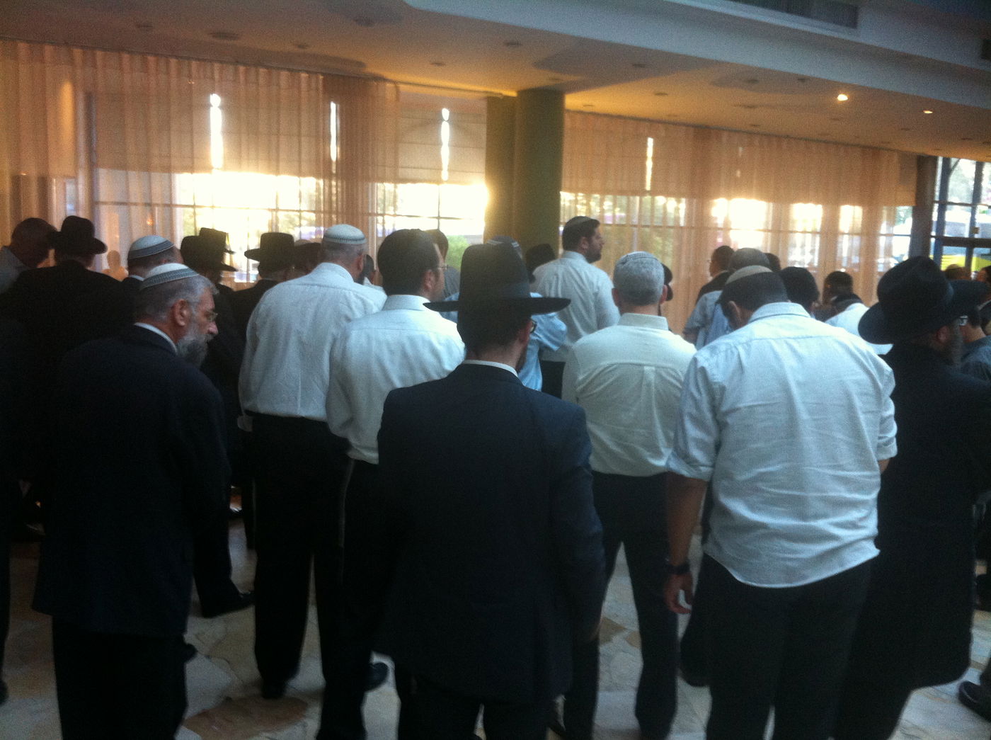 מה לא נאמר על הבזאר שהתנהל במהלך ההצבעה בבחירות לרבנות הראשית? המועמדים ואנשי המטה שלהם עמדו ביום רביעי שעבר בלובי של מלון ליאונרדו בירושלים, חיכו לחברי הגוף הבוחר וממש ליוו אותם בשכנועים של הרגע האחרון, כמעט עד הטלת המעטפה בקלפי. ובתוך כל הפוליטיקה הזו מסביב, הנה תיעוד של כמה דקות נדירות של הסכמה. אנשי כל המטות התכנסו בפינה לתפילת מנחה משותפת • צילום סלולרי: ידידיה מאיר