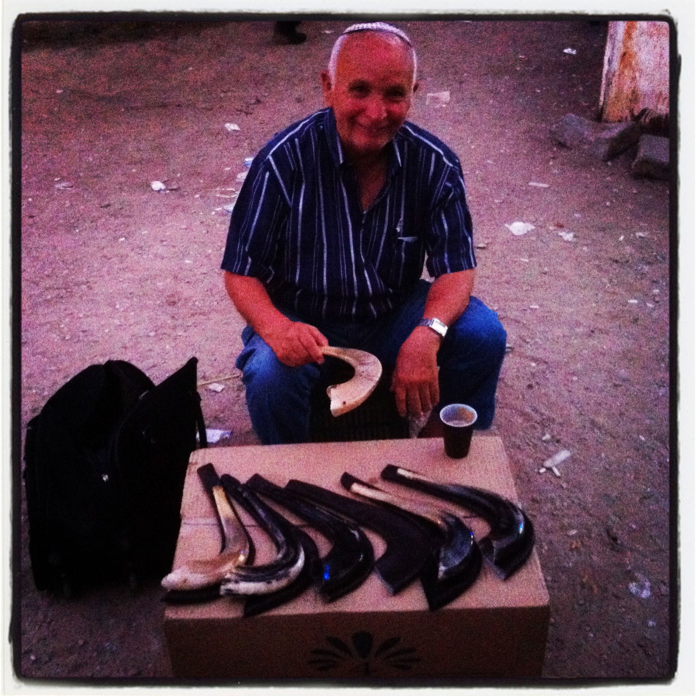 התמונה הזו צולמה השבוע ארבע דקות לפני שקיעת החמה והתקדש חודש אלול. תוך כדי תפילת מנחה בבית הכנסת 'קהל חסידים' שבמרכז רובע ז' באשדוד, שמעתי פתאום תקיעות שופר ותהיתי אם באשדוד נוהגים לתקוע בשופר כבר במנחה האחרונה של חודש אב. כשיצאתי, ראיתי את הבאסטה המאולתרת הזאת של ג'איס ביטון, שעלה לפני 15 שנה מצרפת ומאז מתגורר בעיר. הוא הניח לרגע את כוס הקפה, והסביר לי במבטא צרפתי כבד למה אני צריך, ממש חייב, לקנות ממנו שופר: "הרי מה היה אצלנו בויטרינה, בסלון של כל בית יהודי בצרפת, ולפני זה במרוקו? שלושה דברים: מגילת אסתר, תפילין ישנות של הסבא או של הסבא-רבא, ושופר. ולמה? כדי שהילד ייכנס וישאל את אבא מה זה, והוא יגיד לו: 'זו מגילת אסתר, קוראים אותה בפורים, וזה תפילין מניחים כל בוקר, והשופר הוא לחודש אלול ותשרי, חוזרים בתשובה'. אז תקנה שופר, תקנה. לא לחודש אלול. אתה צריך את זה לכל השנה". צילום סלולרי: ידידיה מאיר