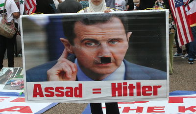 מפגינה נושאת שלט המשווה בין אסד והיטלר