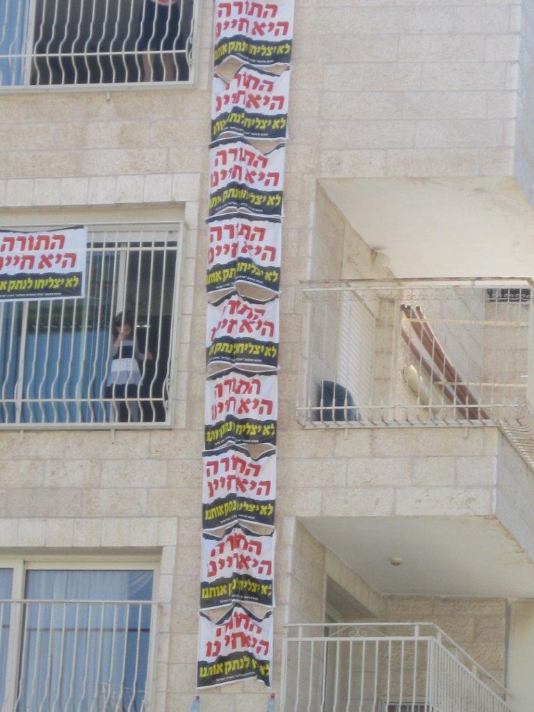 שלטי מחאה נתלו בקריית בעלזא: "לא יצליחו לנתק אותנו"