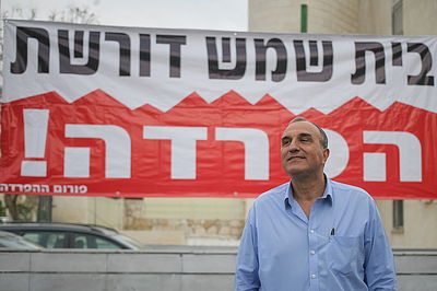 אלי כהן על רקע שלט הדורש הפרדה בבית-שמש