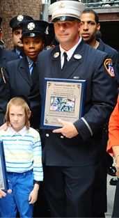 הכבאי מקבל תעודת הוקרה לצד הילד שהציל