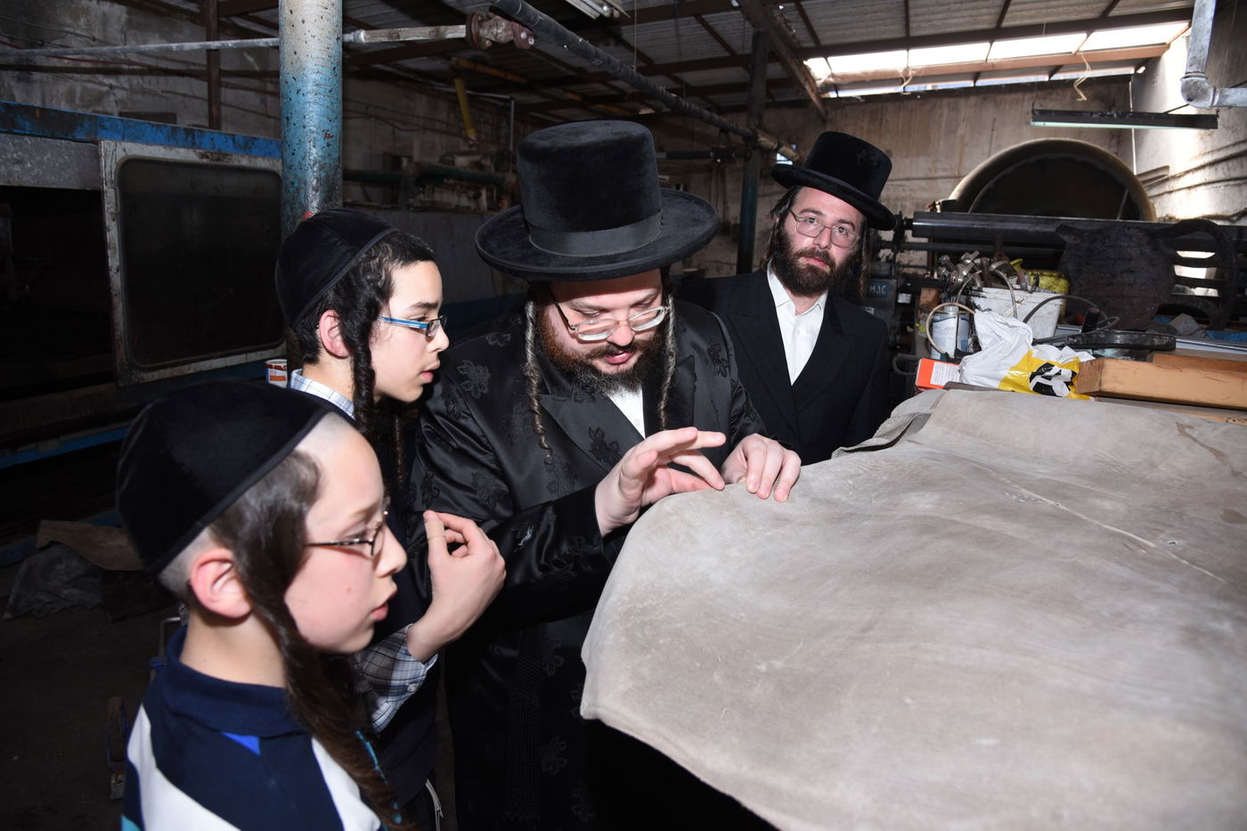 בן הרבי מבעלזא בהכנת רצועות ובתי תפילין לבנו • תיעוד