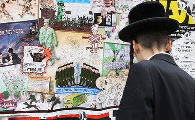 בחור ישיבה לצד מודעות נגד חיילים חרדים