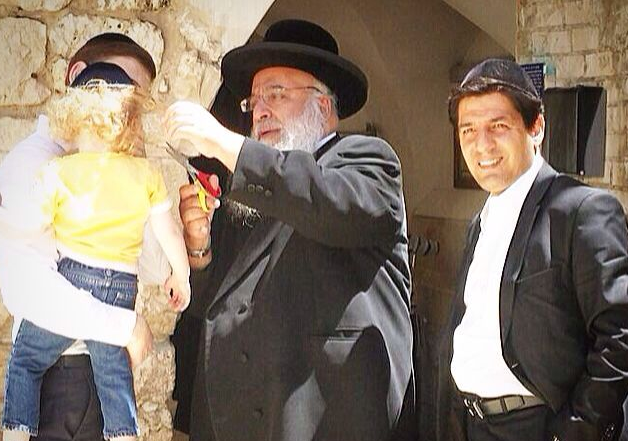 הגר"ב שמואלי גוזר משערותיו של בלום. מימין: עוזרו ר' מרדכי חסידים