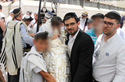 וזאת התורה. חתן בר המצווה חובק את ספר התורה. מימין, הרב משה כהן, איש יד לאחים שהופקד על הפקת המעמד