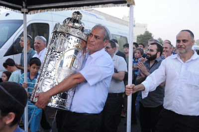 הזוכה עם ספר התורה בתהלוכה ברחובה של עיר