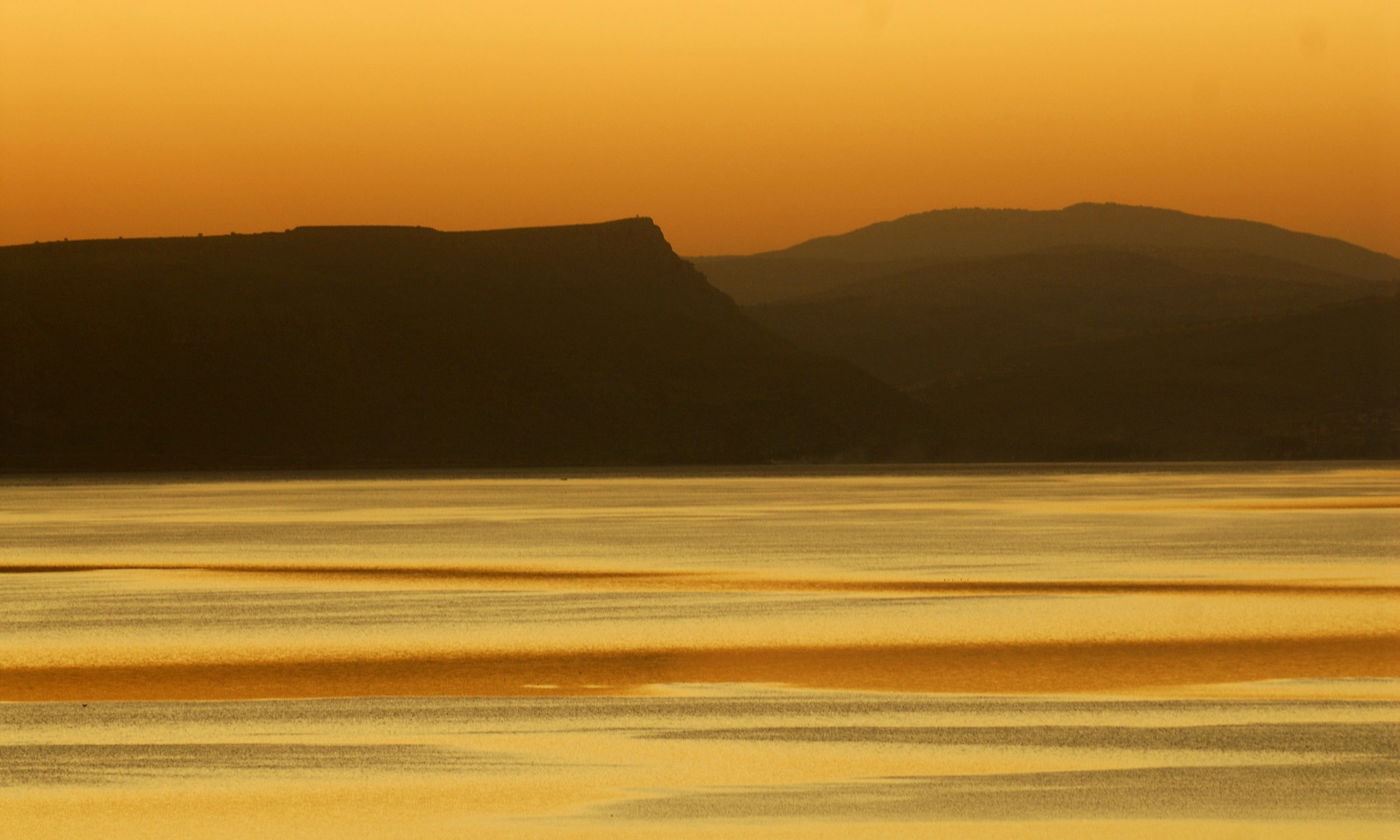 השתקפות שקיעת השמש על אגם הכנרת. ברקע, הר הארבל
