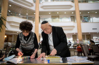 זוג מבוגרים מדליקים נרות חנוכה