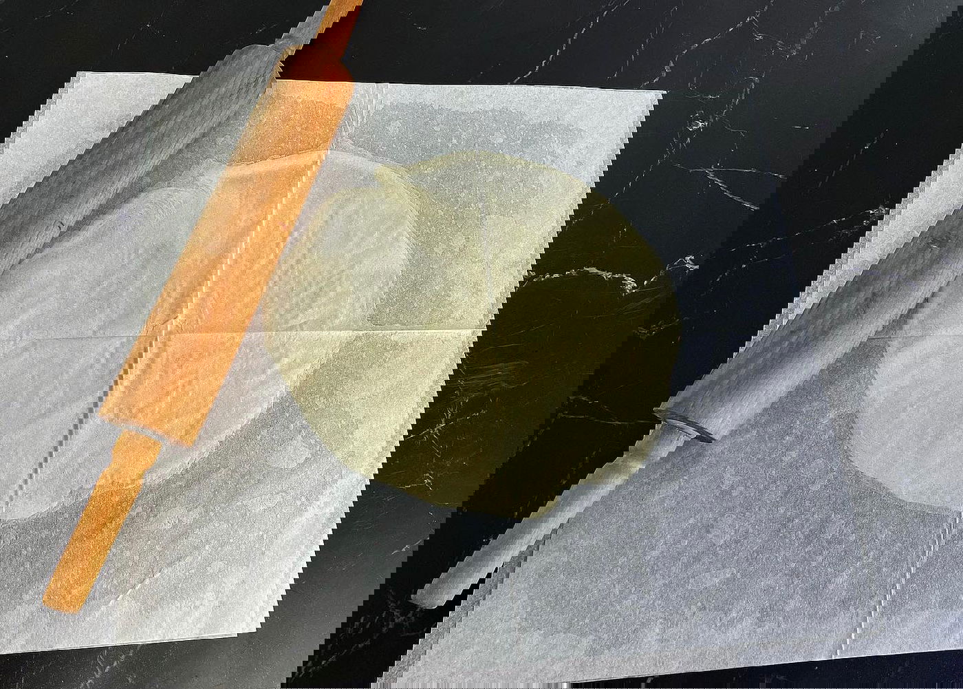 מכסים עם נייר אפייה משומן ומרדדים לעיגול דק