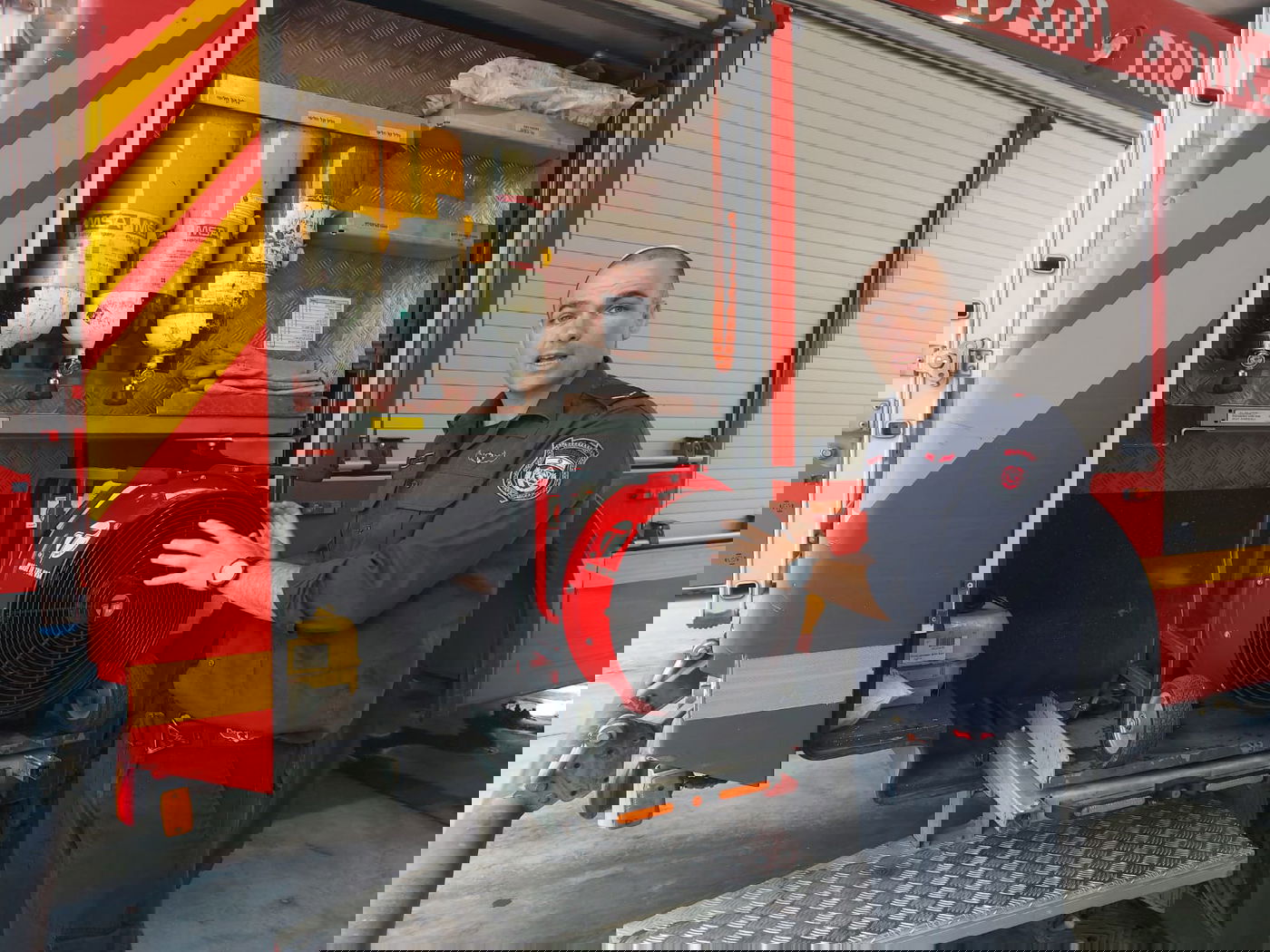 "האסון שלנו זה שאיפת עשן". מאוורר עוצמתי לפיזור עשן, מעליו: מסיכות חמצן בעת כניסה לאש