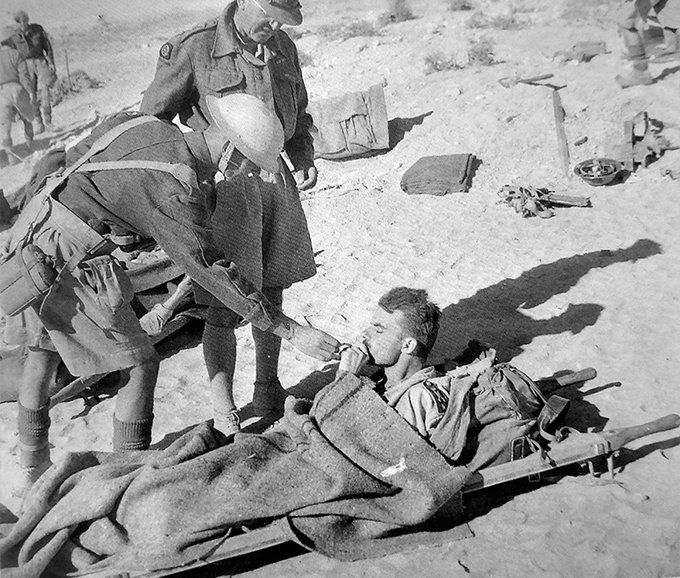 חיילים בריטיים מציתים סיגריה של חייל איטלקי פצוע באל-עלמיין. מצרים 1942