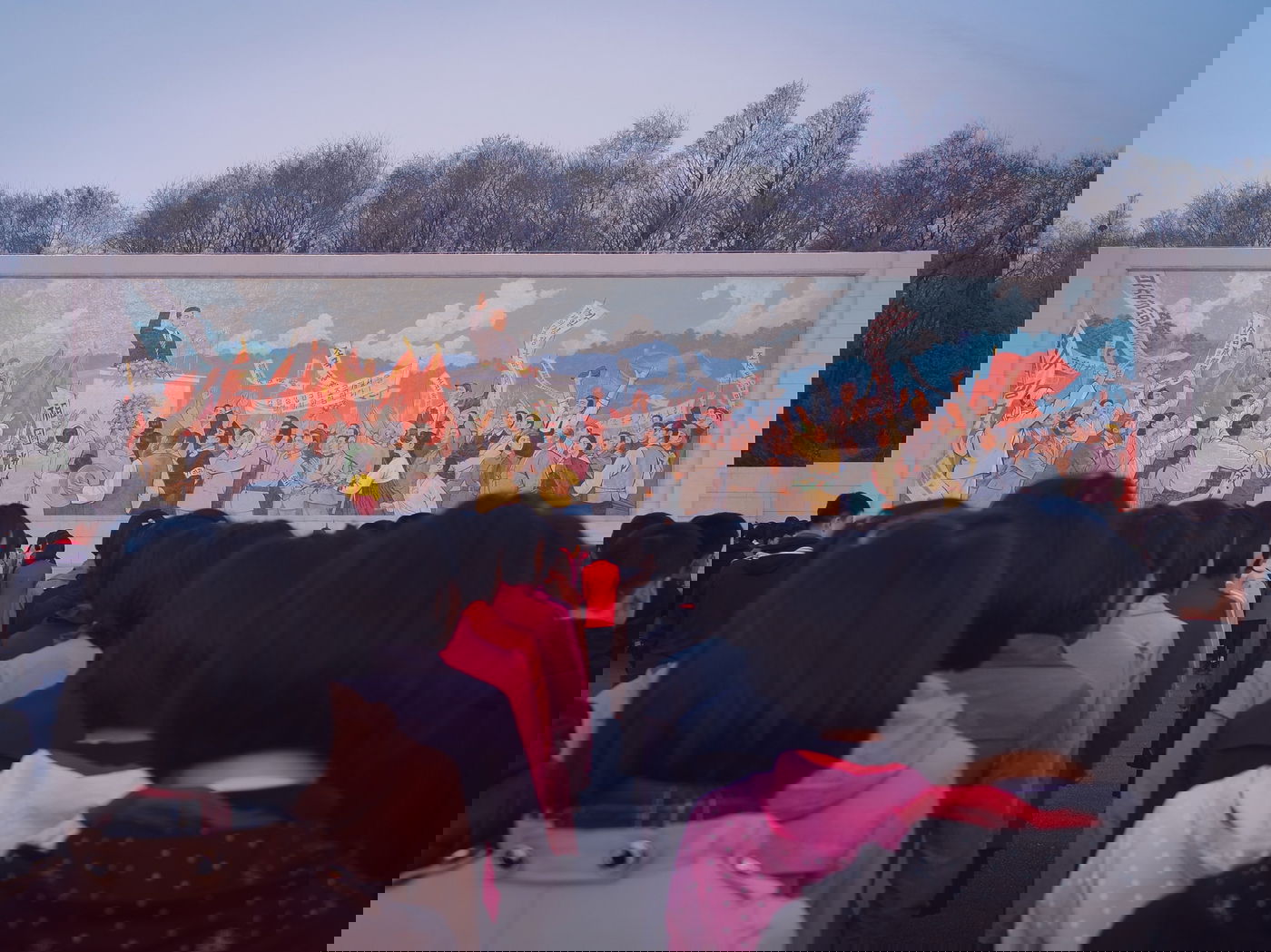 ילדים עומדים בתור מול ציור קיר בפיונגיאנג, צפון קוריאה