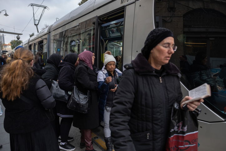 אשה חרדית מתפללת בירידה מהרכבת הקלה. צילום אילוסטרציה