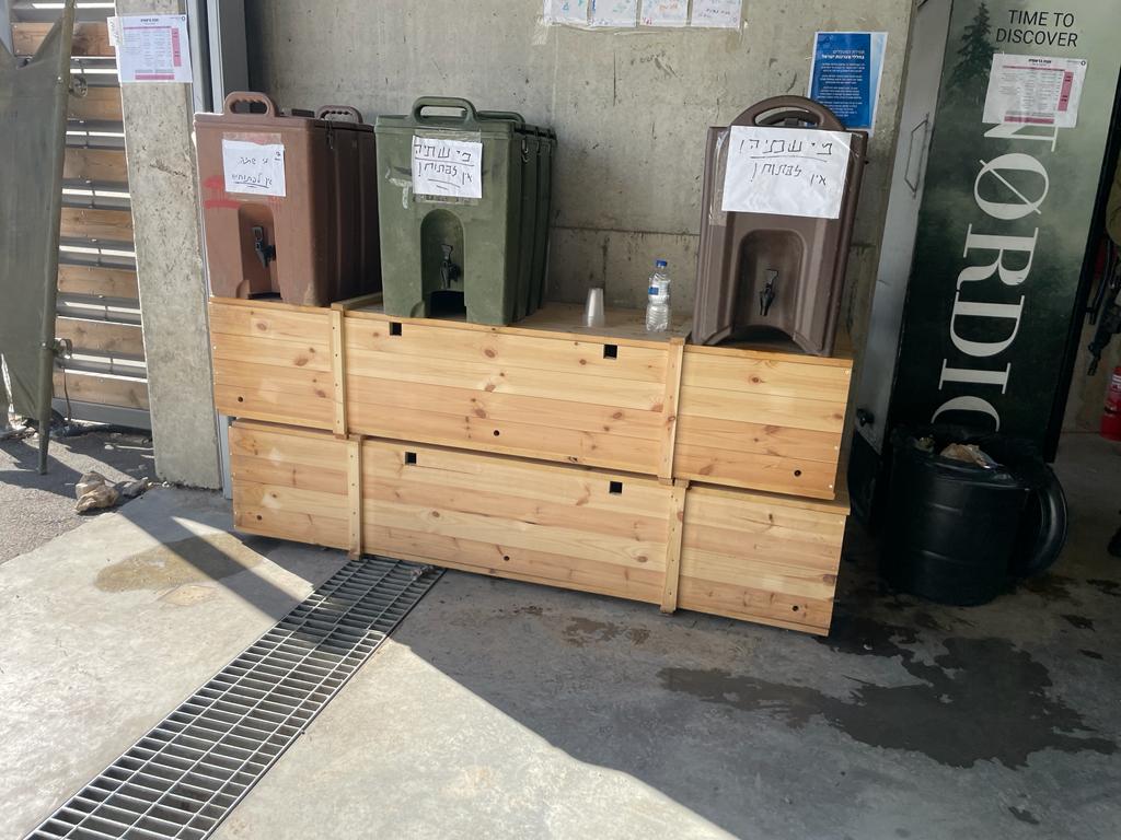 אין שולחן להניח עליו את מיכלי המים עבור אנשי החברה קדישא - בבסיס שורה, אז משתמשים בארגזי קבורה