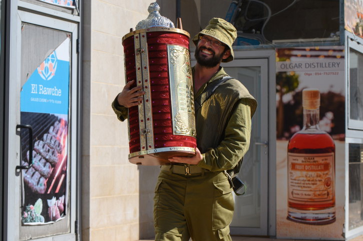 חייל מחזיק בספר תורה סמוך לגבול הצפוני