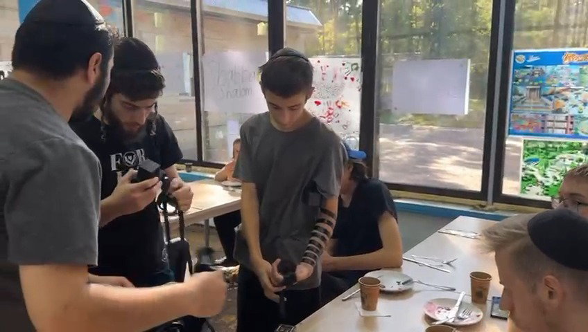 נער מניח תפילין לראשונה בחייו, ביום האחרון של המחנה