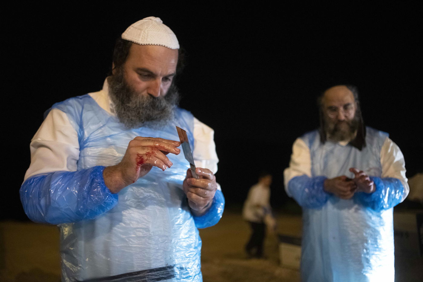 שוחט בבדיקת הסכין לשחיטת תרנגולי הכפרות