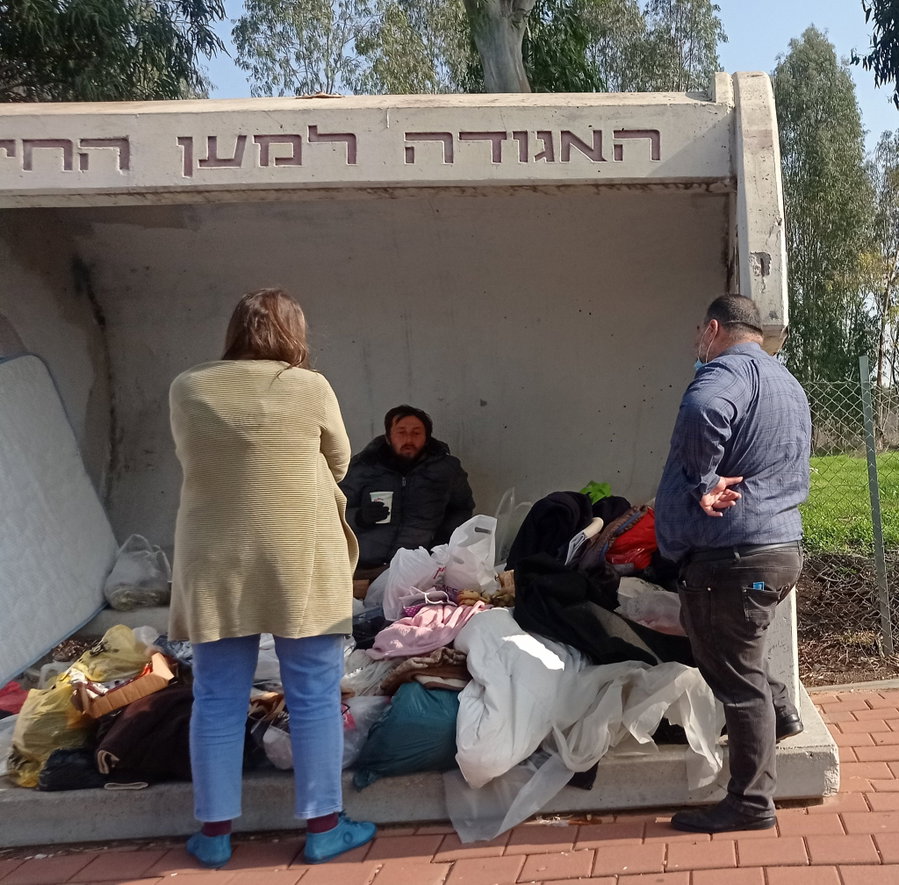 אנשים עוזרים לחסר בית שמתגורר בתחנת אוטובוס