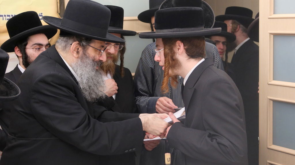 הגה"צ רבי צבי מאיר זילברברג בחלוקת שוברי השטריימלעך לחתנים
