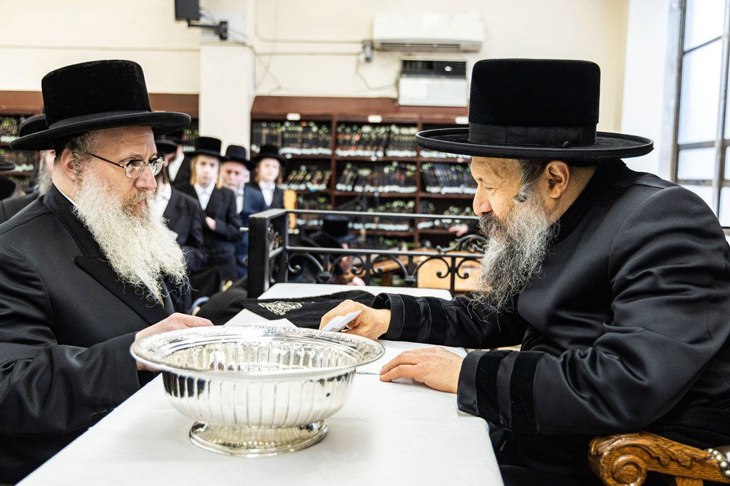חסידי באבוב 45 נותנים קוויטלעך לרבם לפני המסע לצאנז