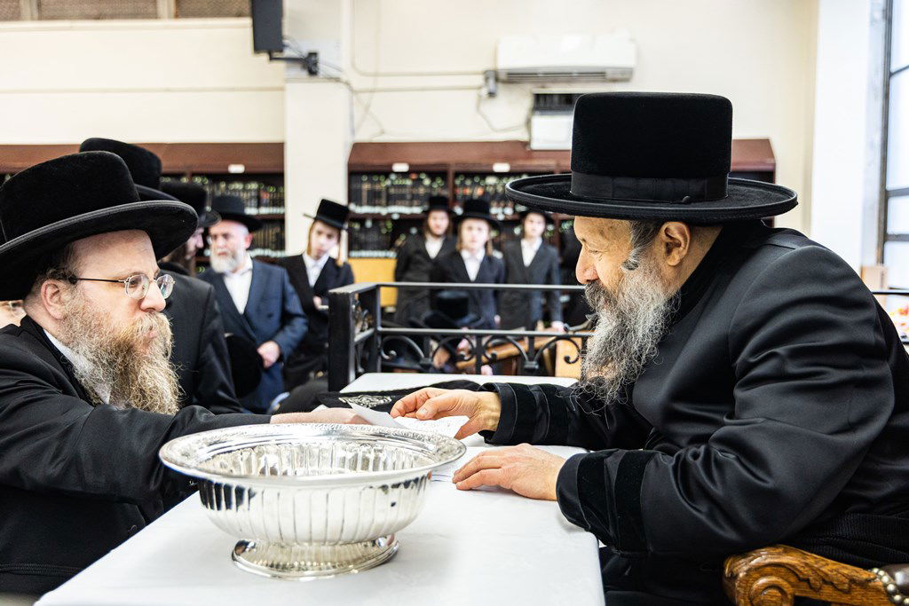 חסידי באבוב 45 נותנים קוויטלעך לרבם לפני המסע לצאנז