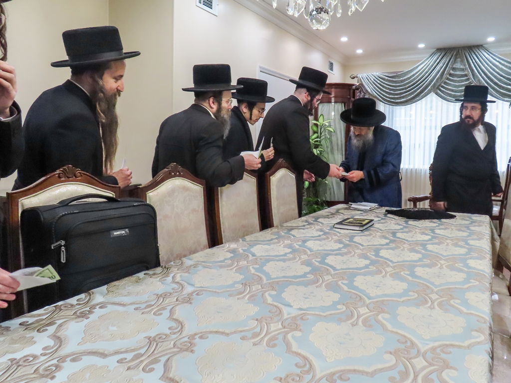 חסידי באבוב 45 נותנים קוויטלעך לרבם לפני המסע לצאנז