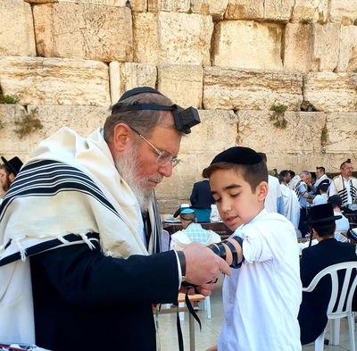 הרב הראשי מניח תפילין לנכדו 