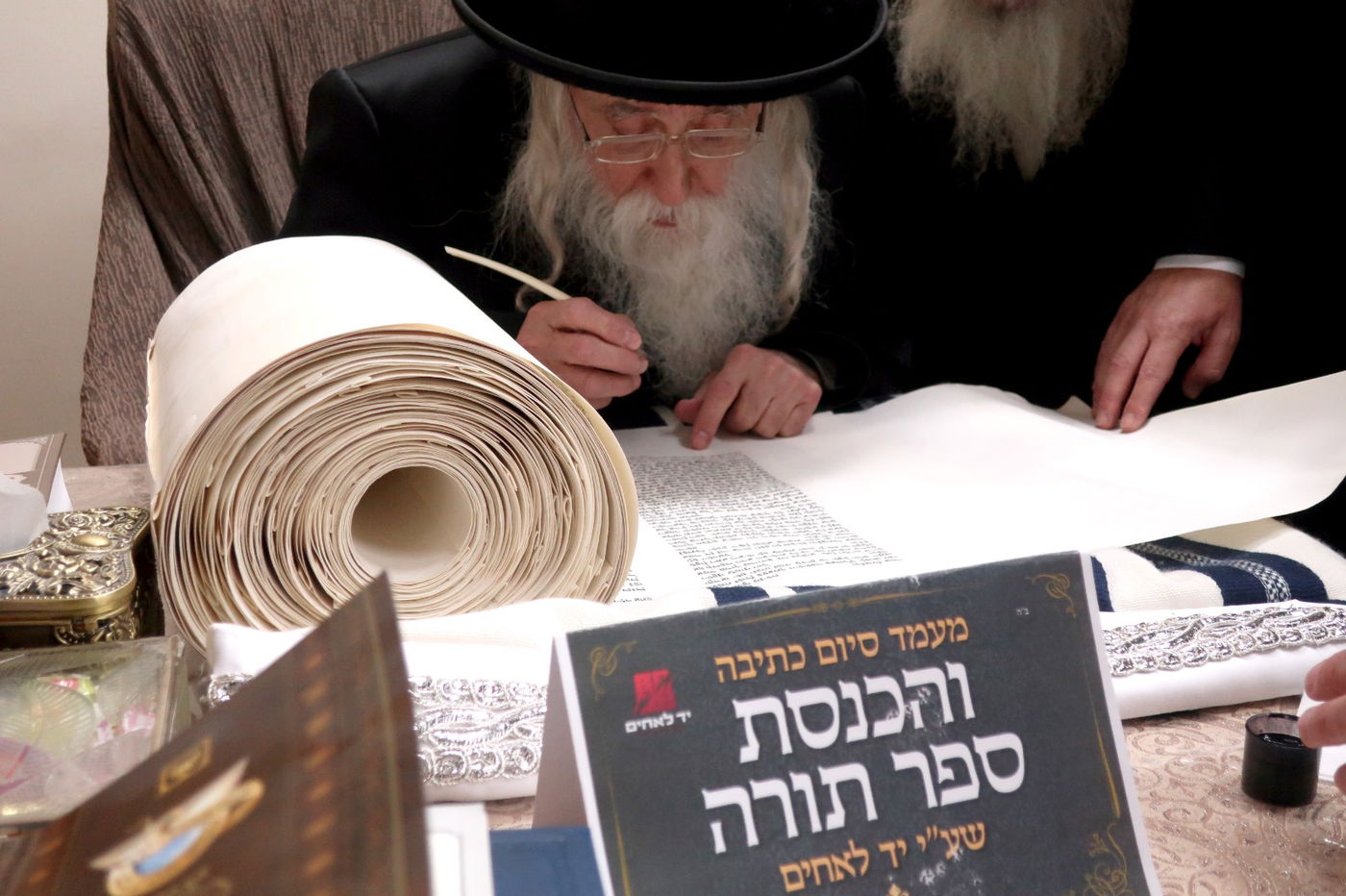 האדמו"ר ממחנובקא בכתיבת אות בספר התורה של יד לאחים