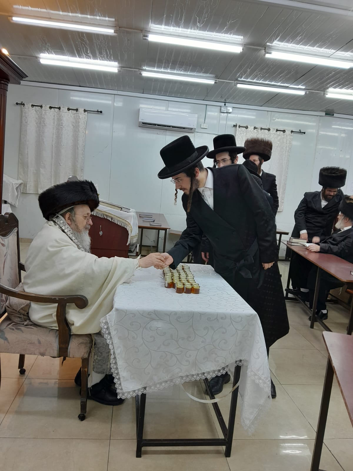 האדמו"ר מקאליש בחלוקת צנצנות דבש לאחר סליחות