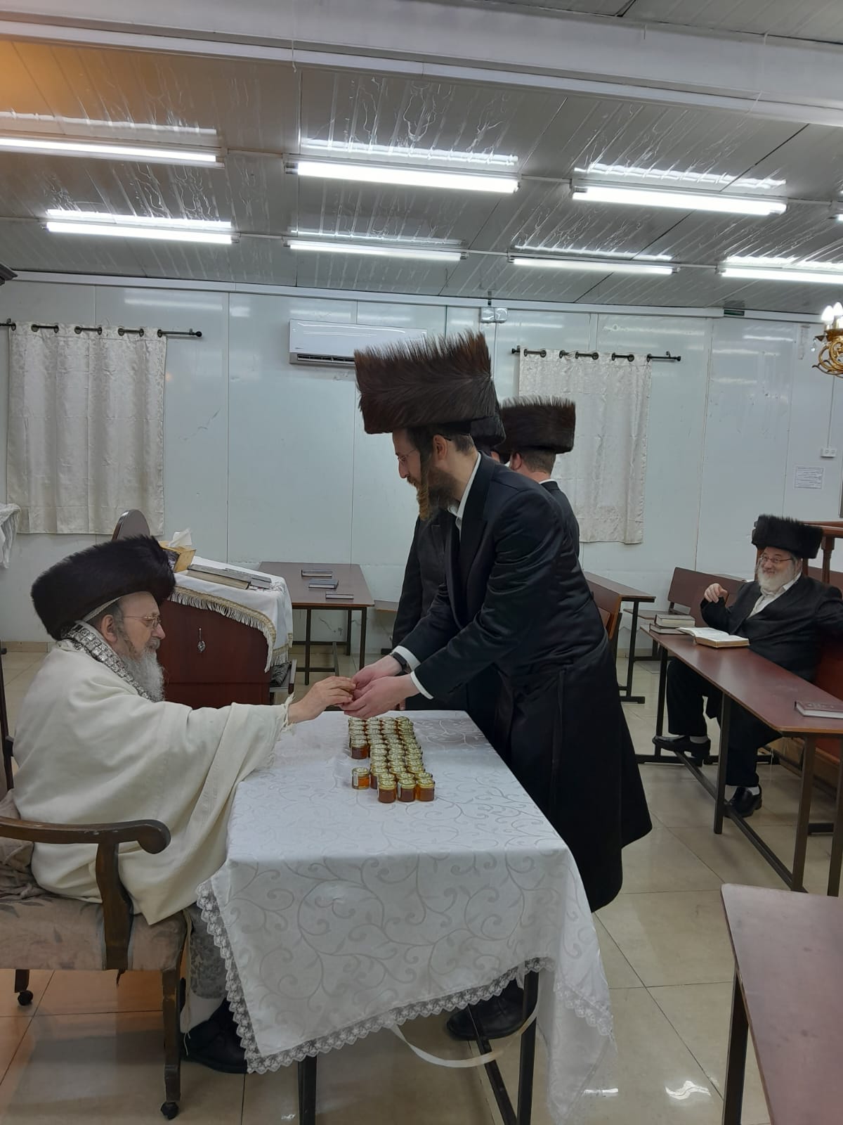 האדמו"ר מקאליש בחלוקת צנצנות דבש לאחר סליחות