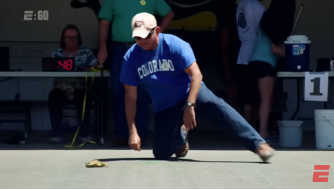 משתתף מעודד את הצפרדע שלו לקפוץ במהלך התחרות