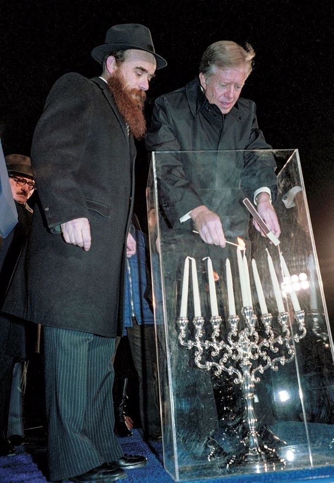 קרטר ברגעי ההדלקה בתש"מ, לצד הרב שם טוב