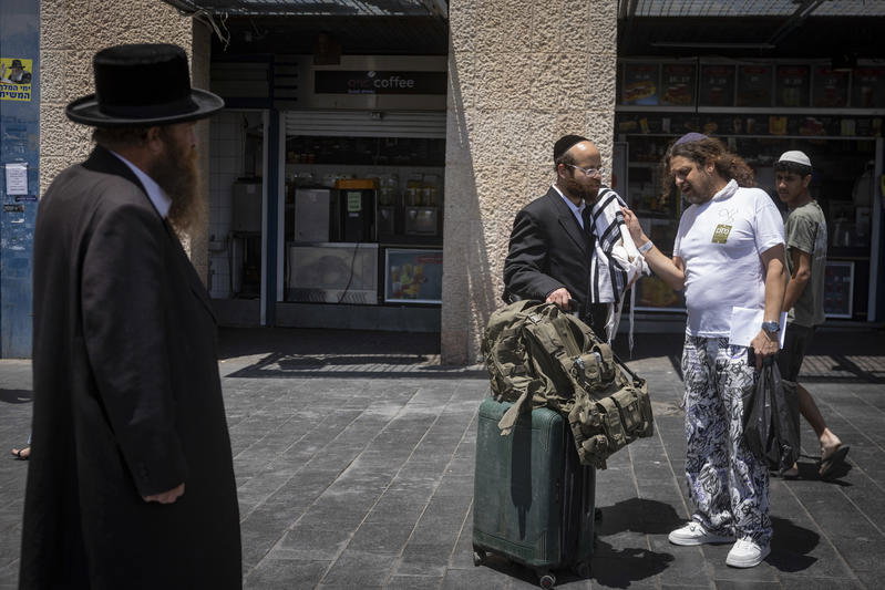 חסיד גור תועד בדרך למילואים; אנשים נעצרו לנשק את ספר התורה שבידיו