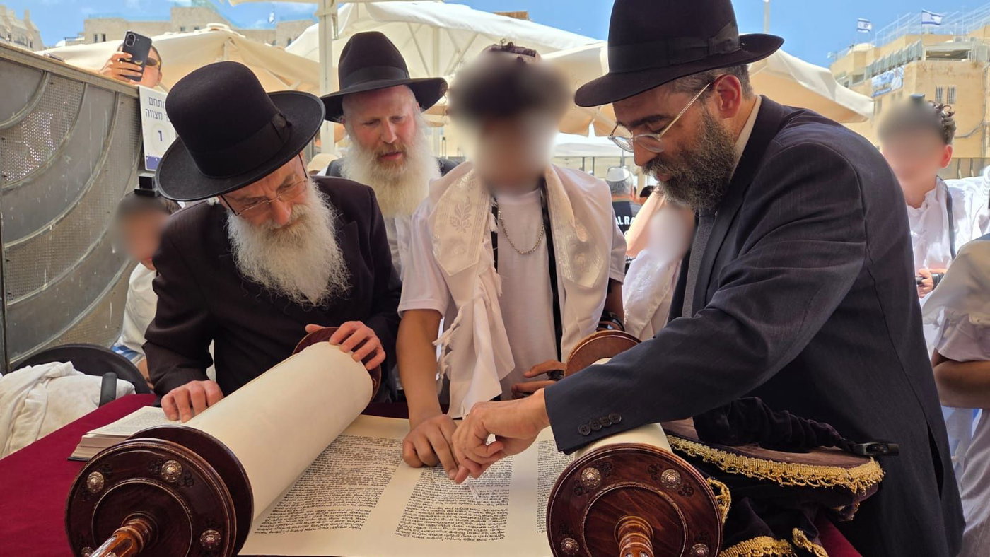  אחד הנערים החתנים עולה לתורה בלווית הרב אליעזר מנחם ברוידא, שתרם את שמונה זוגות התפילין, והרב זאב רובינסון, מפעילי יד לאחים