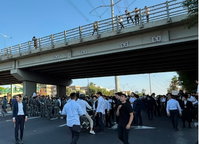 פקקי ענק במרכז הארץ, כביש 4 חסום לתנועה; מפגינים מחזיקים טלאי צהוב ושרים על הכביש | צפו