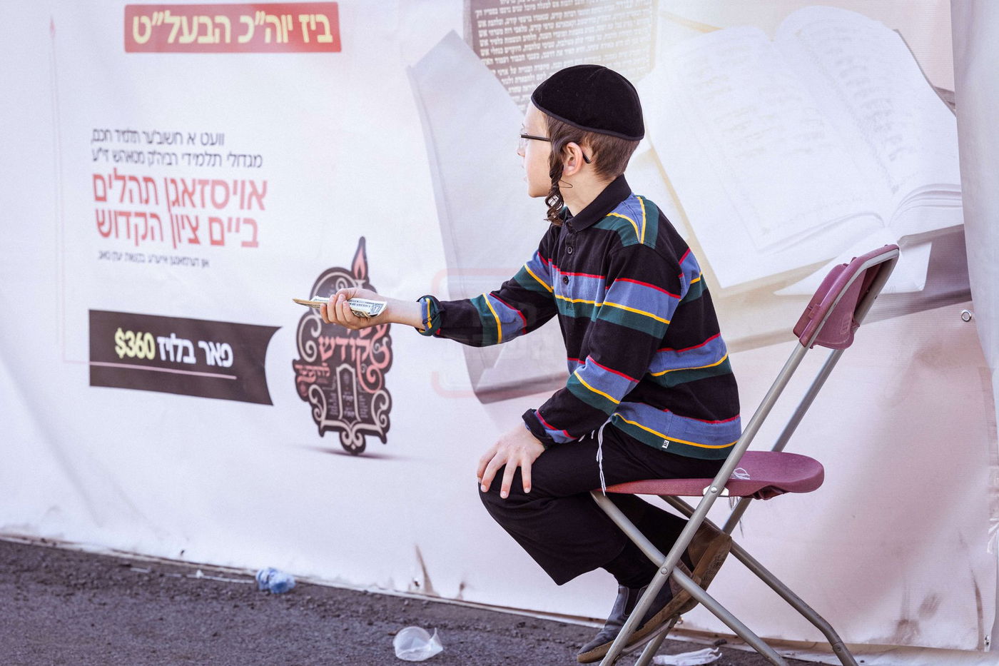 ילד חסידי מקבץ צדקה מחסידים בדרכם אל הציון הקדוש בטאהש